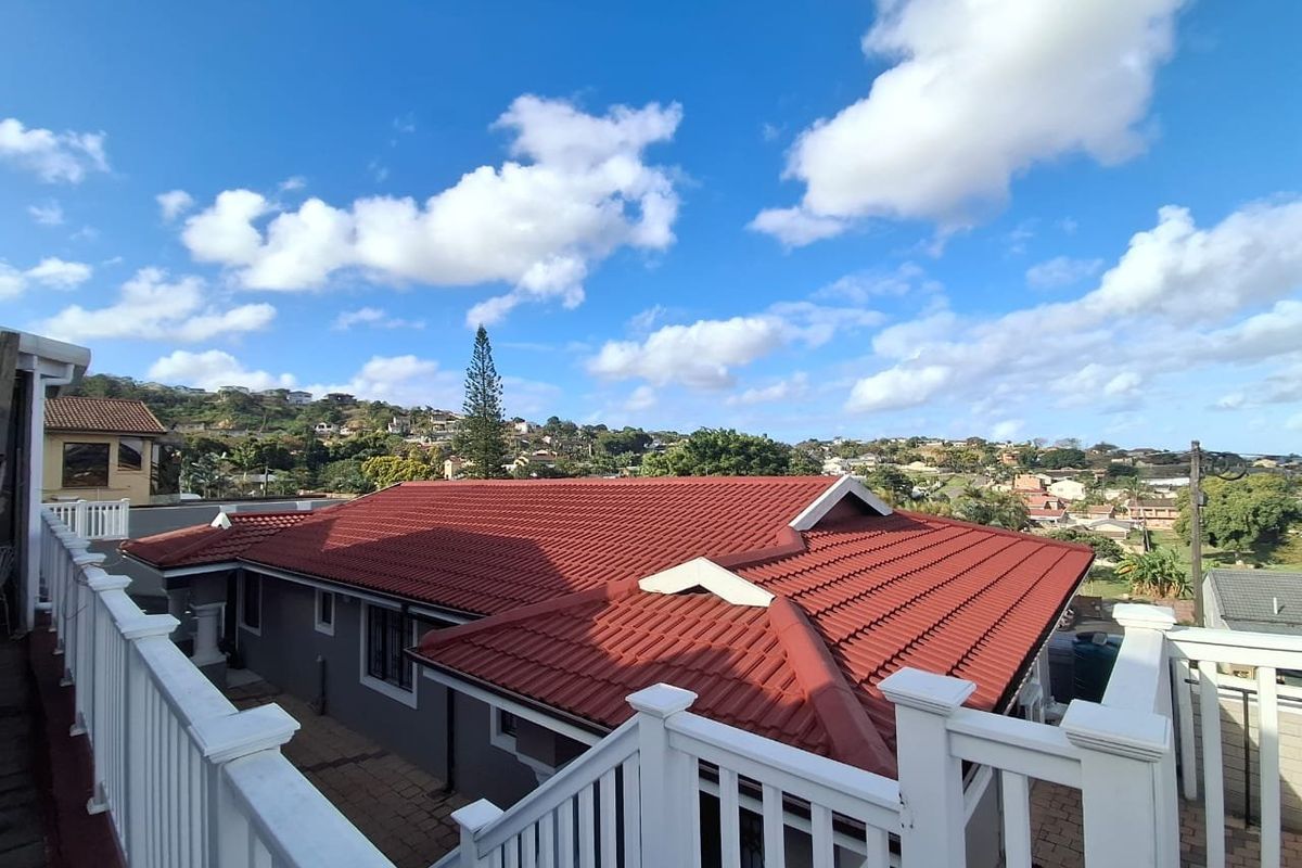 Elevated view of the rear exterior featuring a well-maintained tiled roof, white railings, and paved patio area overlooking the surrounding neighborhood.