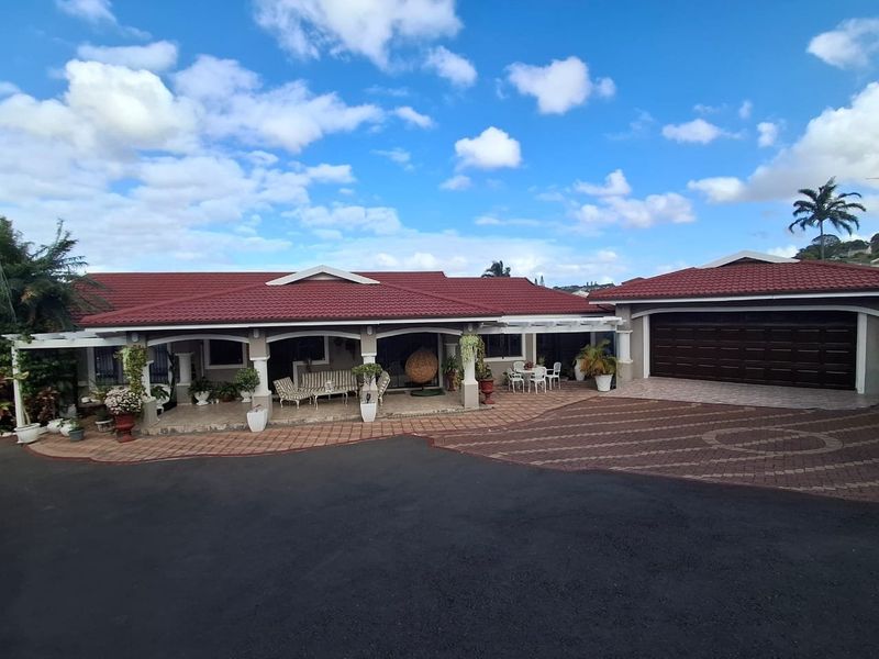 A well-maintained single-story residence featuring a covered patio, tiled roof, and an integrated double garage with a spacious paved driveway.