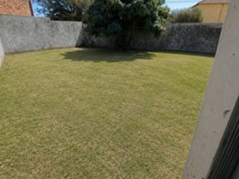 A private rear garden featuring a well-maintained lawn enclosed by perimeter boundary walls.