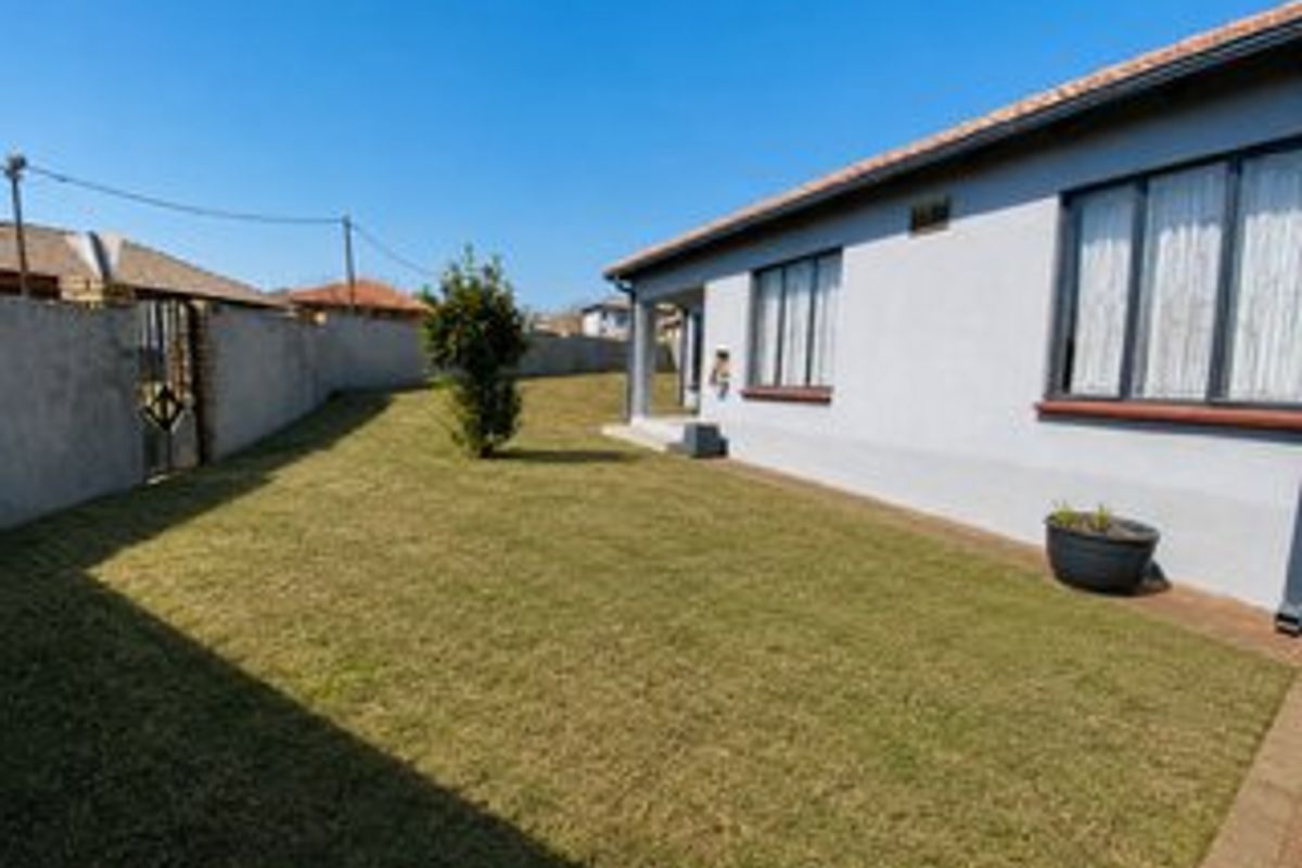 A well-maintained rear garden featuring a neat lawn, paved walkway, and perimeter wall, providing a private outdoor space for the property.
