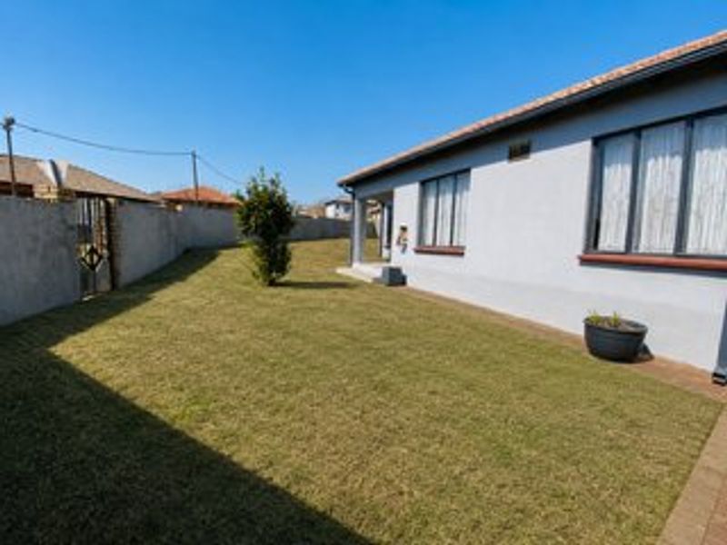 A well-maintained rear garden featuring a neat lawn, paved walkway, and perimeter wall, providing a private outdoor space for the property.
