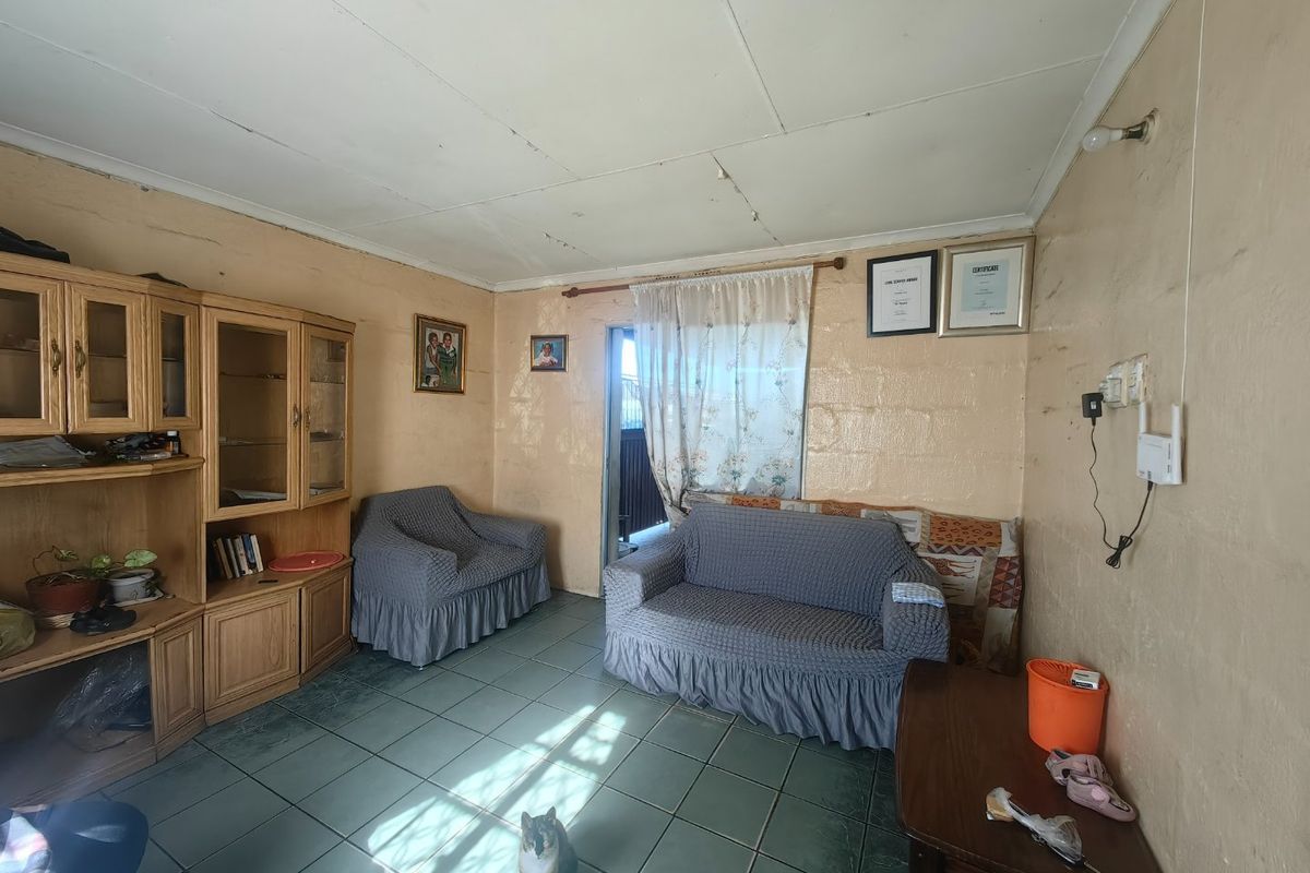 A living room featuring tiled flooring and ceiling panels, currently requiring cosmetic updates to the walls and ceiling to improve the overall aesthetic.