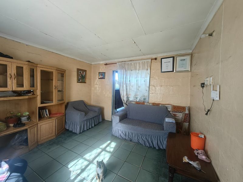 A living room featuring tiled flooring and ceiling panels, currently requiring cosmetic updates to the walls and ceiling to improve the overall aesthetic.