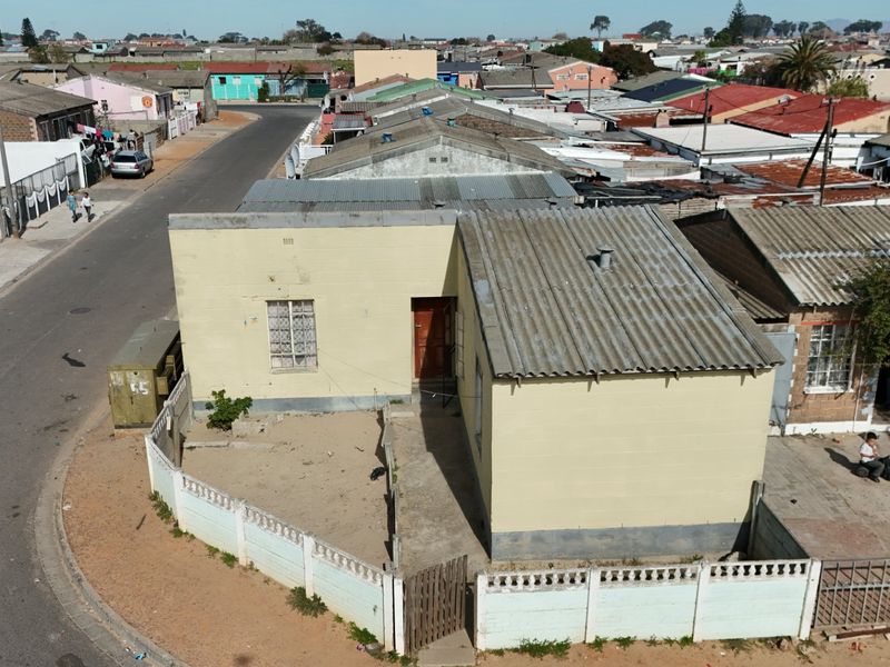 Aerial view of a single-story residential property featuring a corrugated iron roof, masonry exterior, and a fenced front yard area.