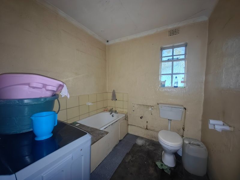 A dated bathroom featuring a bathtub and toilet, currently requiring significant renovation and cosmetic updates to improve its condition and functionality.