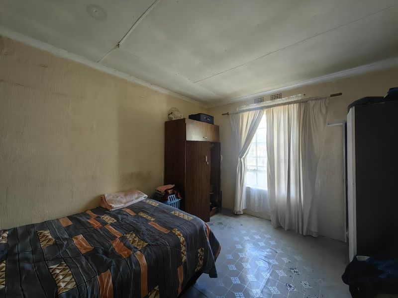 A bedroom featuring tiled flooring and a window, currently requiring cosmetic updates to the walls and ceiling to improve its overall condition.