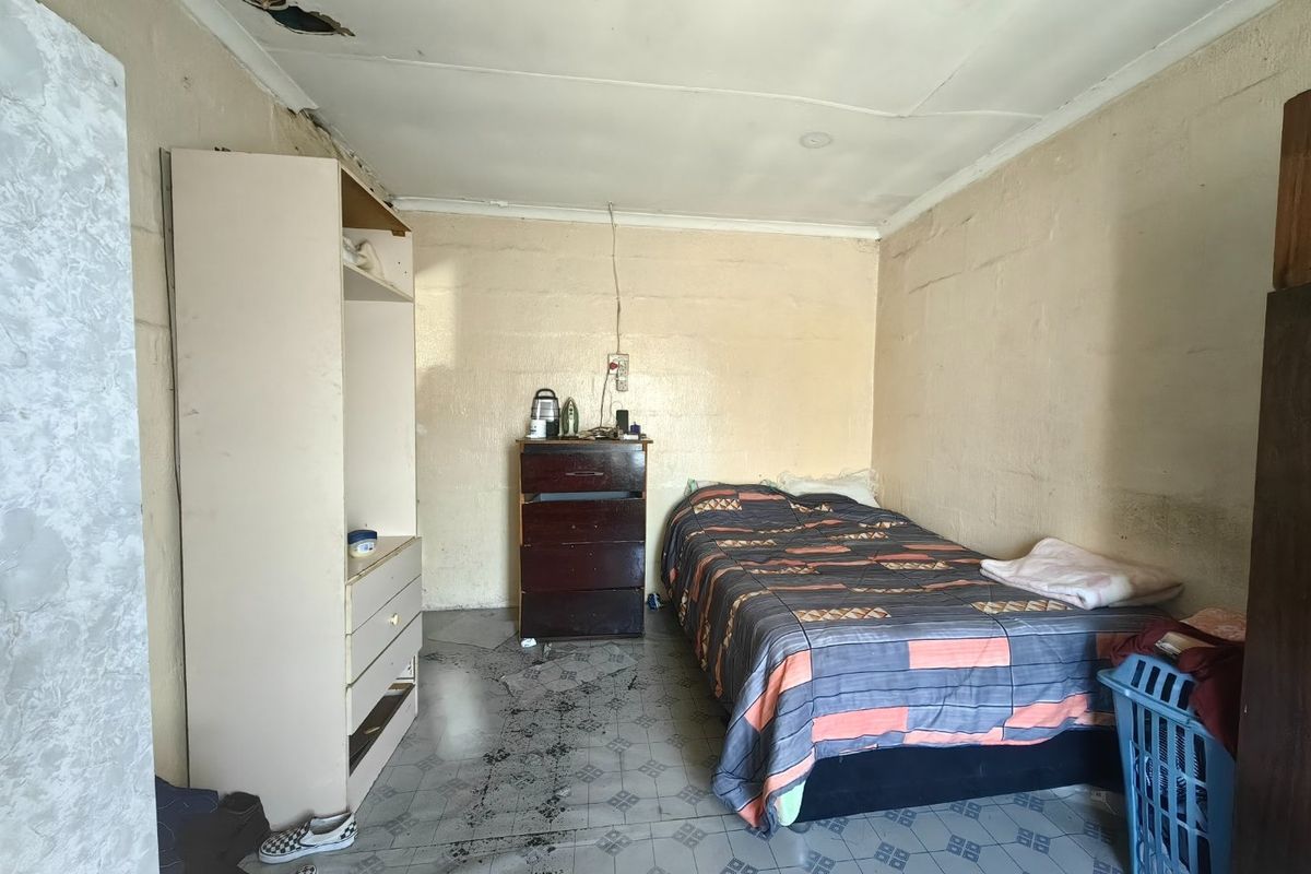 A bedroom featuring tiled flooring and requiring ceiling and wall repairs to restore the space.