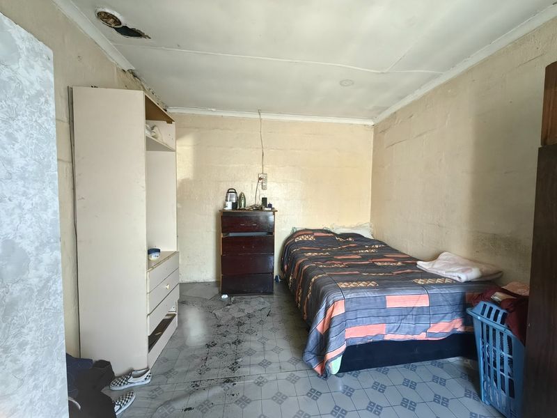 A bedroom featuring tiled flooring and requiring ceiling and wall repairs to restore the space.