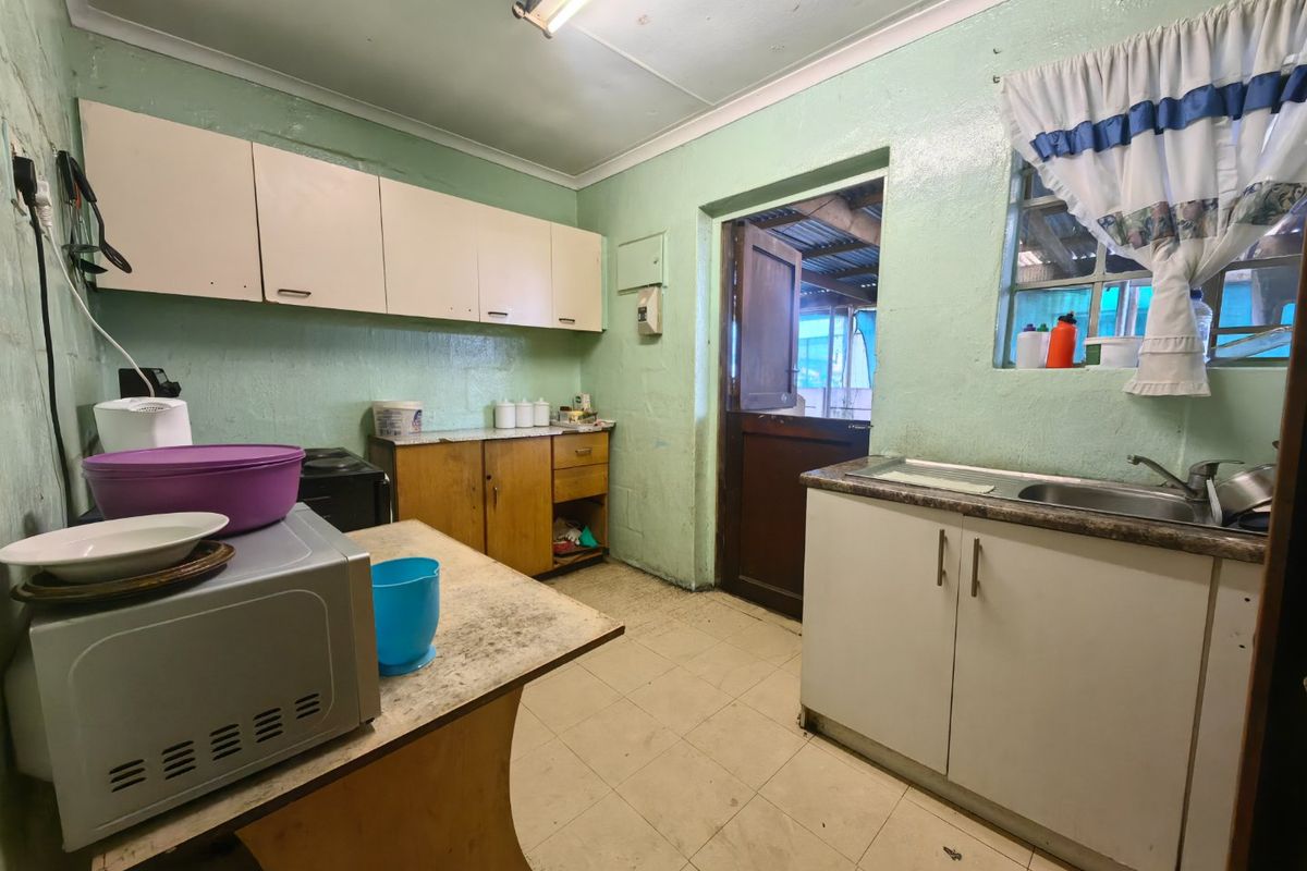A functional kitchen featuring built-in cabinetry, laminate countertops, and a stainless steel sink, with direct access to an outdoor area via a stable door.
