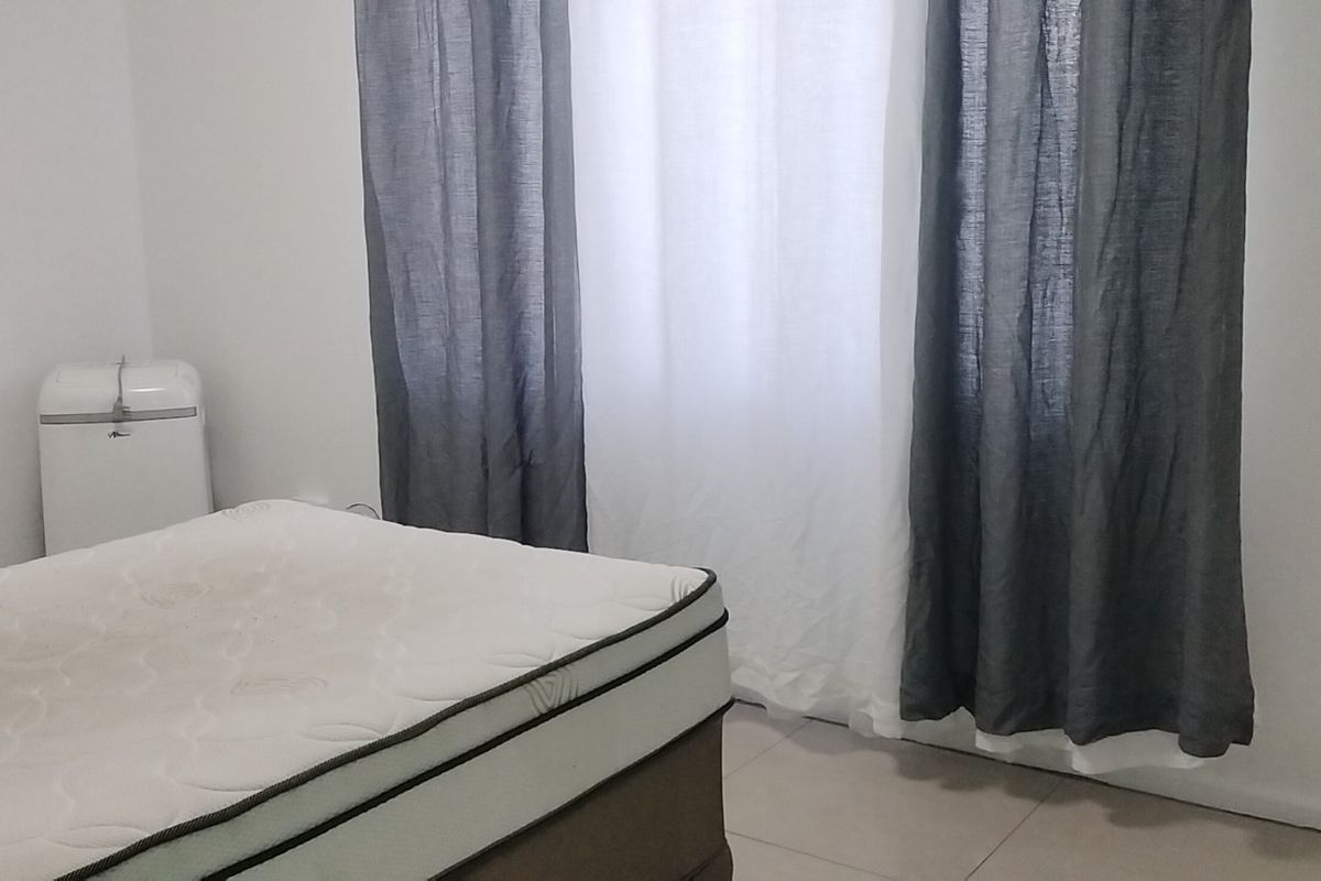 A simple bedroom featuring neutral tiled flooring and white walls, providing a clean and functional space ready for personalization.