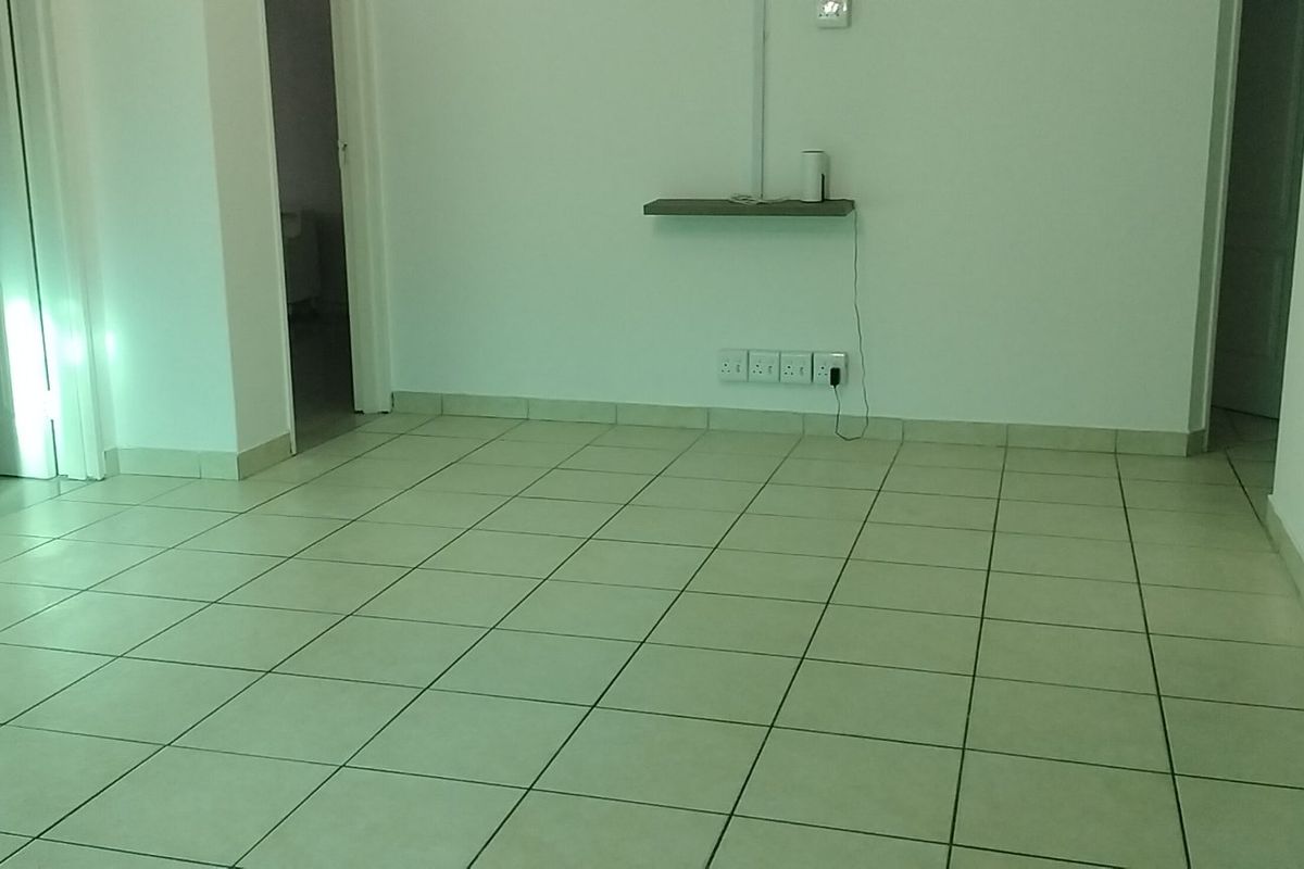 An empty living area featuring neutral tiled flooring and clean white walls, providing a versatile blank canvas for interior design.