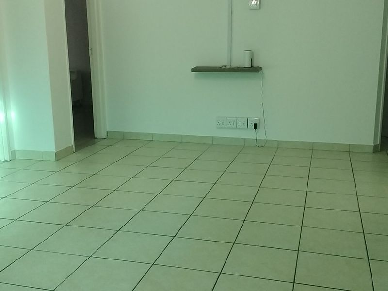 An empty living area featuring neutral tiled flooring and clean white walls, providing a versatile blank canvas for interior design.