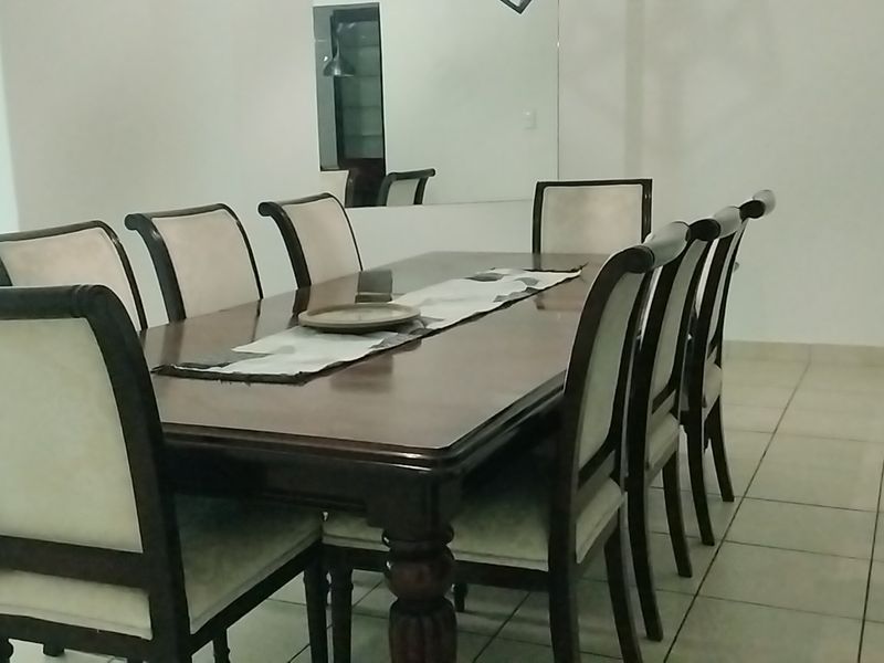 A dining room featuring tiled flooring and a large wall-mounted mirror, providing a functional space for family meals.