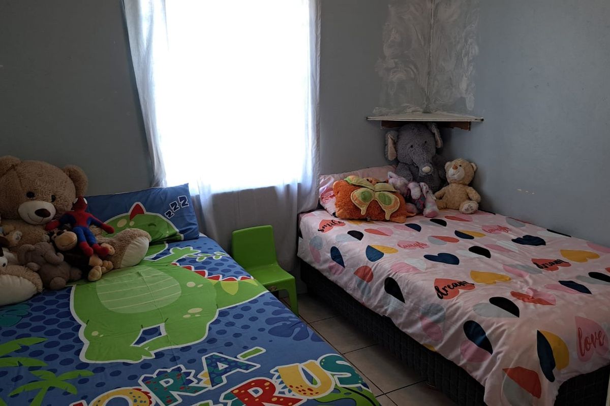 A bedroom featuring a corner shelf and tiled flooring, currently utilized as a children's room.