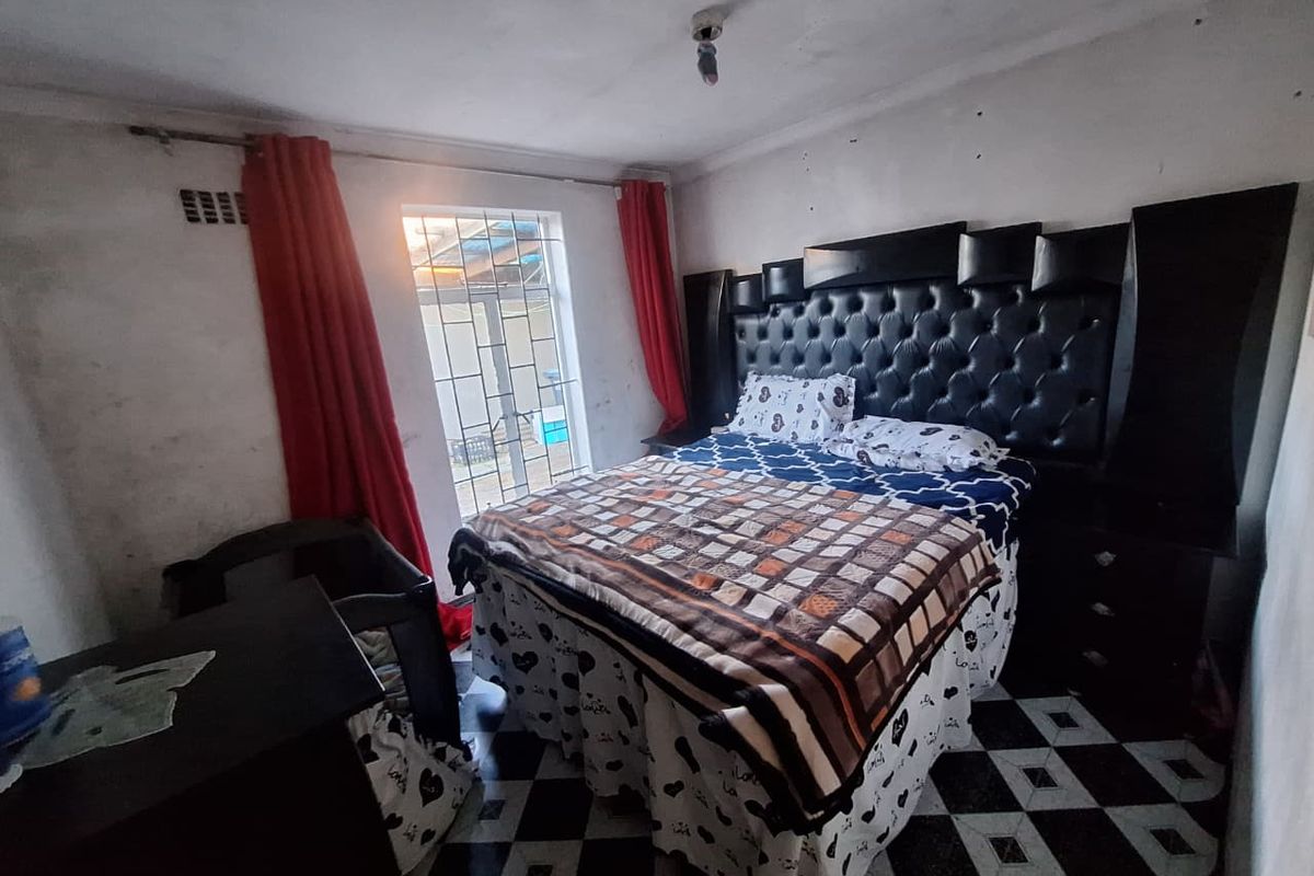A bedroom featuring tiled flooring and a built-in headboard, currently requiring cosmetic updates to the walls and ceiling to improve its overall condition.