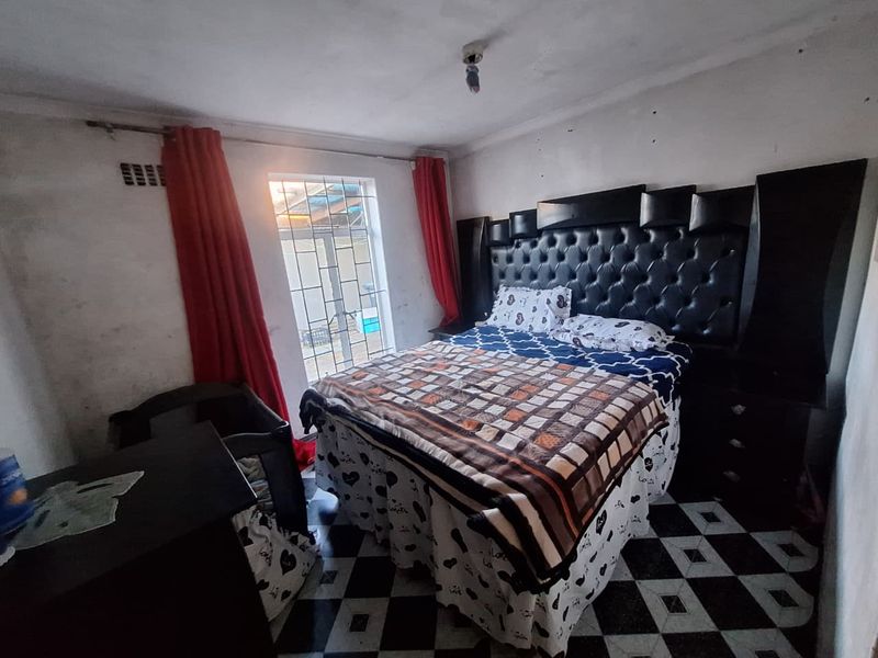 A bedroom featuring tiled flooring and a built-in headboard, currently requiring cosmetic updates to the walls and ceiling to improve its overall condition.