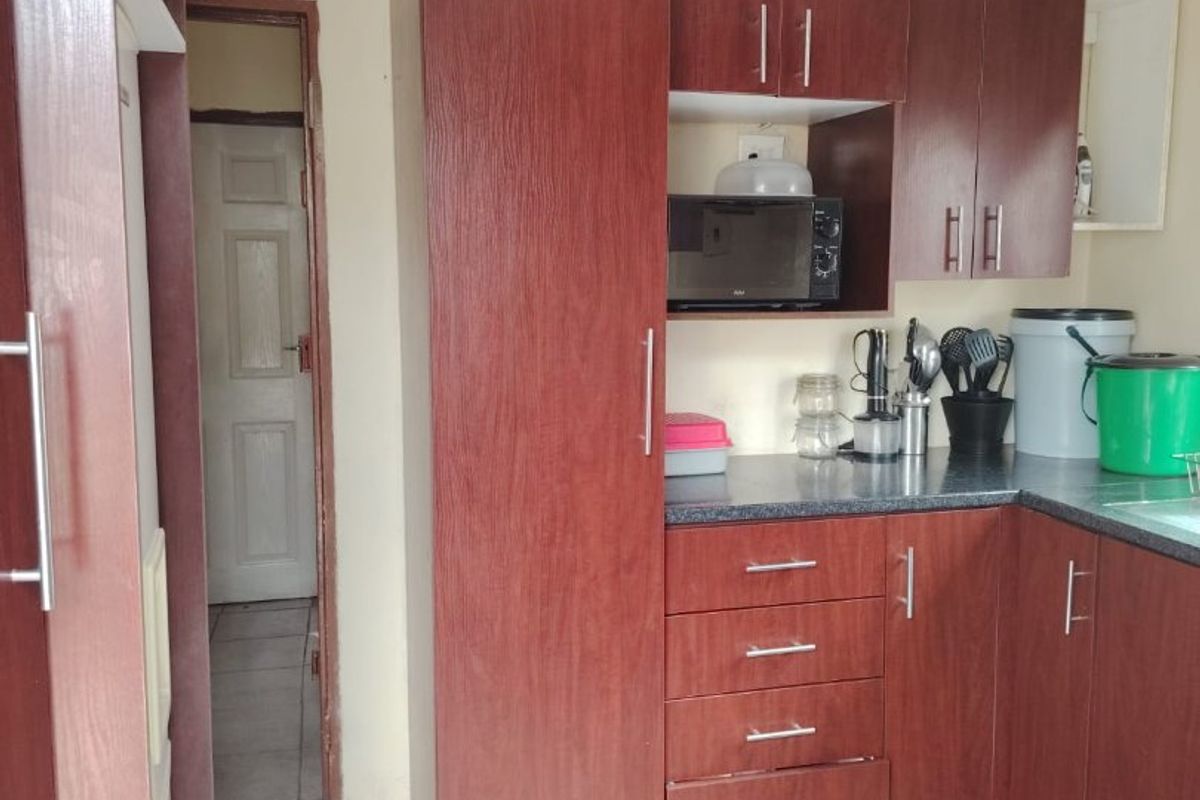 A functional kitchen featuring dark wood-look cabinetry, laminate countertops, and tiled flooring, providing a practical workspace with integrated storage solutions.