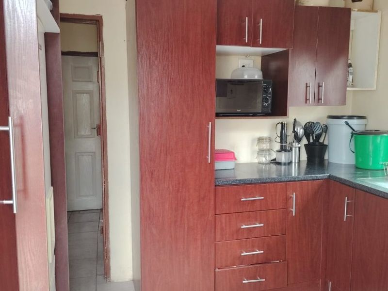 A functional kitchen featuring dark wood-look cabinetry, laminate countertops, and tiled flooring, providing a practical workspace with integrated storage solutions.