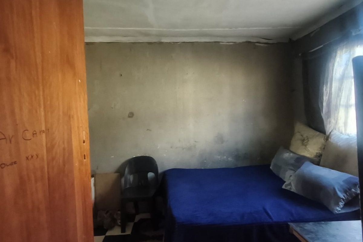 A bedroom featuring checkered floor tiles and a timber door, requiring significant cosmetic updates to the walls and ceiling to improve its overall condition.