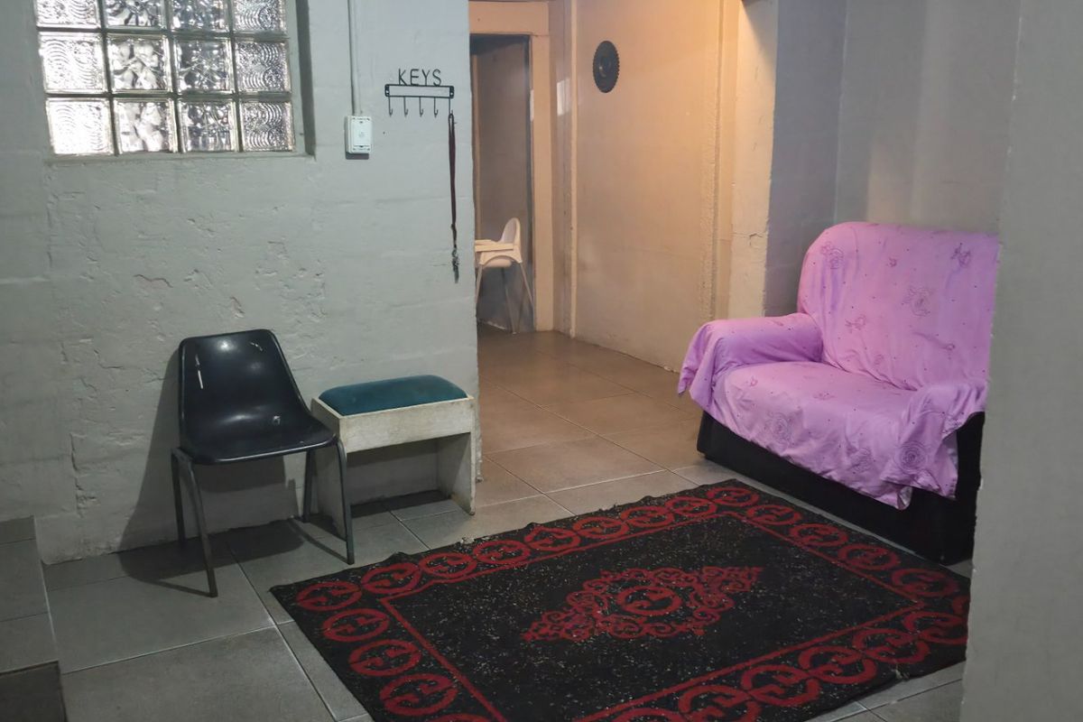 A small living area featuring ceramic floor tiles and a glass block window, providing a functional space with potential for modernization.