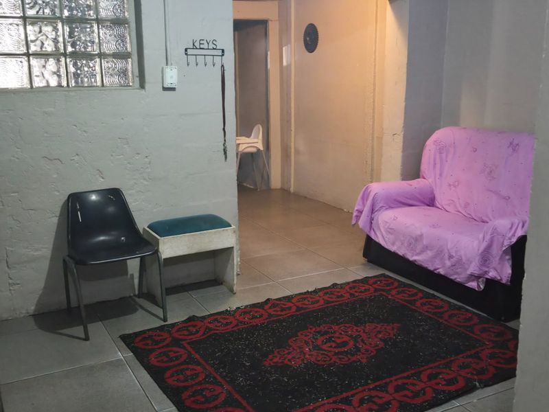 A small living area featuring ceramic floor tiles and a glass block window, providing a functional space with potential for modernization.