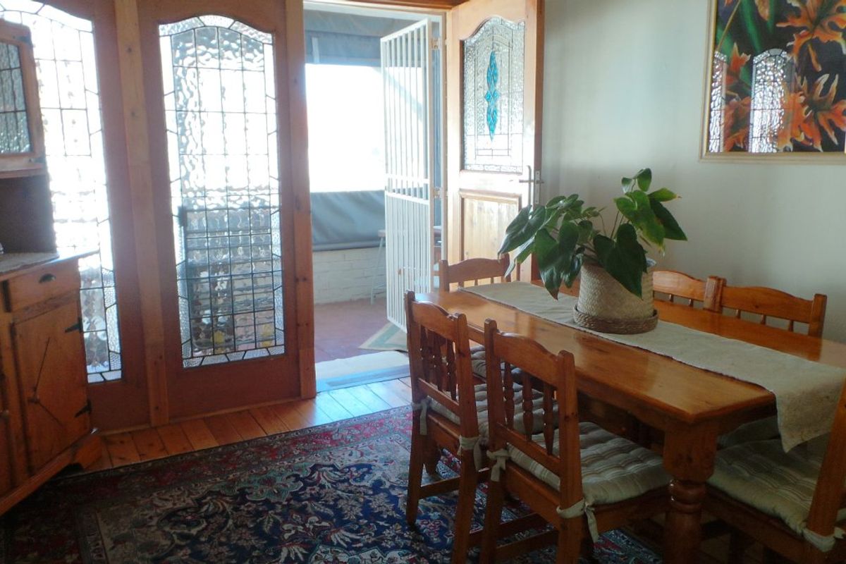 Dining room featuring timber flooring and decorative leaded glass timber doors providing access to an outdoor patio area.