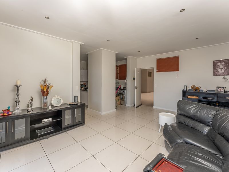 Spacious open-plan living area featuring neutral tiled flooring, recessed downlighting, and a seamless flow into the adjacent kitchen and utility spaces.