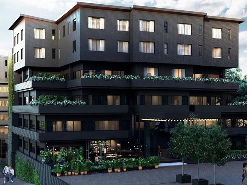 Modern multi-story apartment building exterior featuring dark facade, tiered balconies, and a welcoming ground-level entrance area.