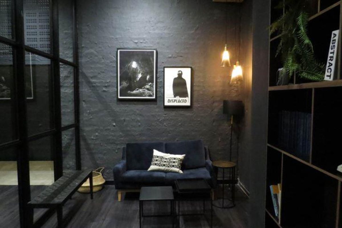 A modern, moody living area featuring dark textured walls, integrated shelving, and contemporary pendant lighting, creating a sophisticated and intimate atmosphere.