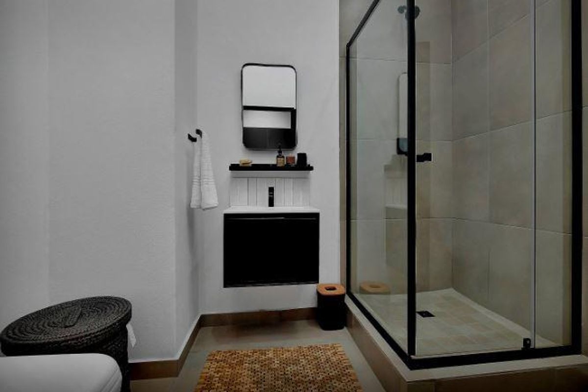 Modern bathroom featuring a walk-in shower with a black-framed glass enclosure and a sleek wall-mounted vanity unit.
