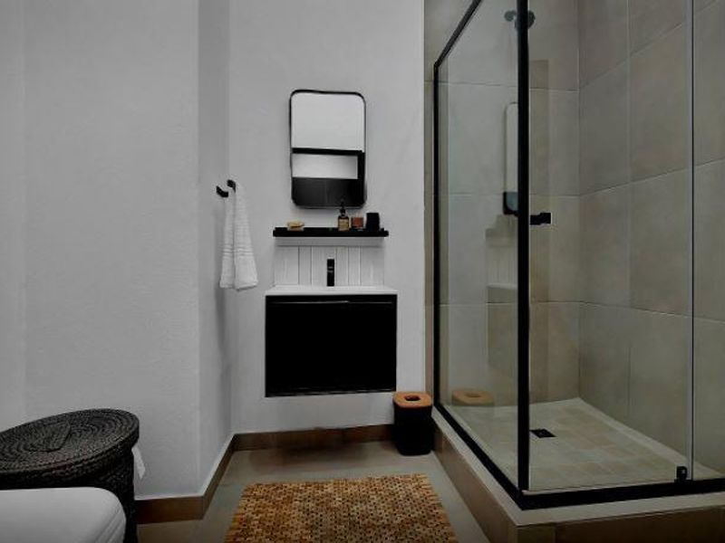 Modern bathroom featuring a walk-in shower with a black-framed glass enclosure and a sleek wall-mounted vanity unit.