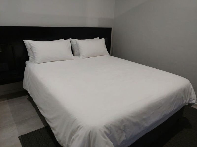A simple bedroom featuring a built-in dark headboard and neutral wall finishes.