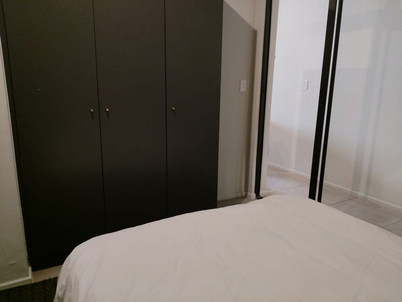 A bedroom featuring a dark built-in wardrobe and a sliding door leading to an adjacent space.