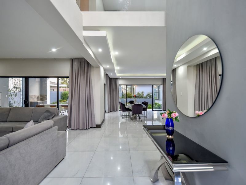 Spacious open-plan living and dining area featuring high ceilings, modern porcelain tiling, and large sliding doors leading to an outdoor patio.