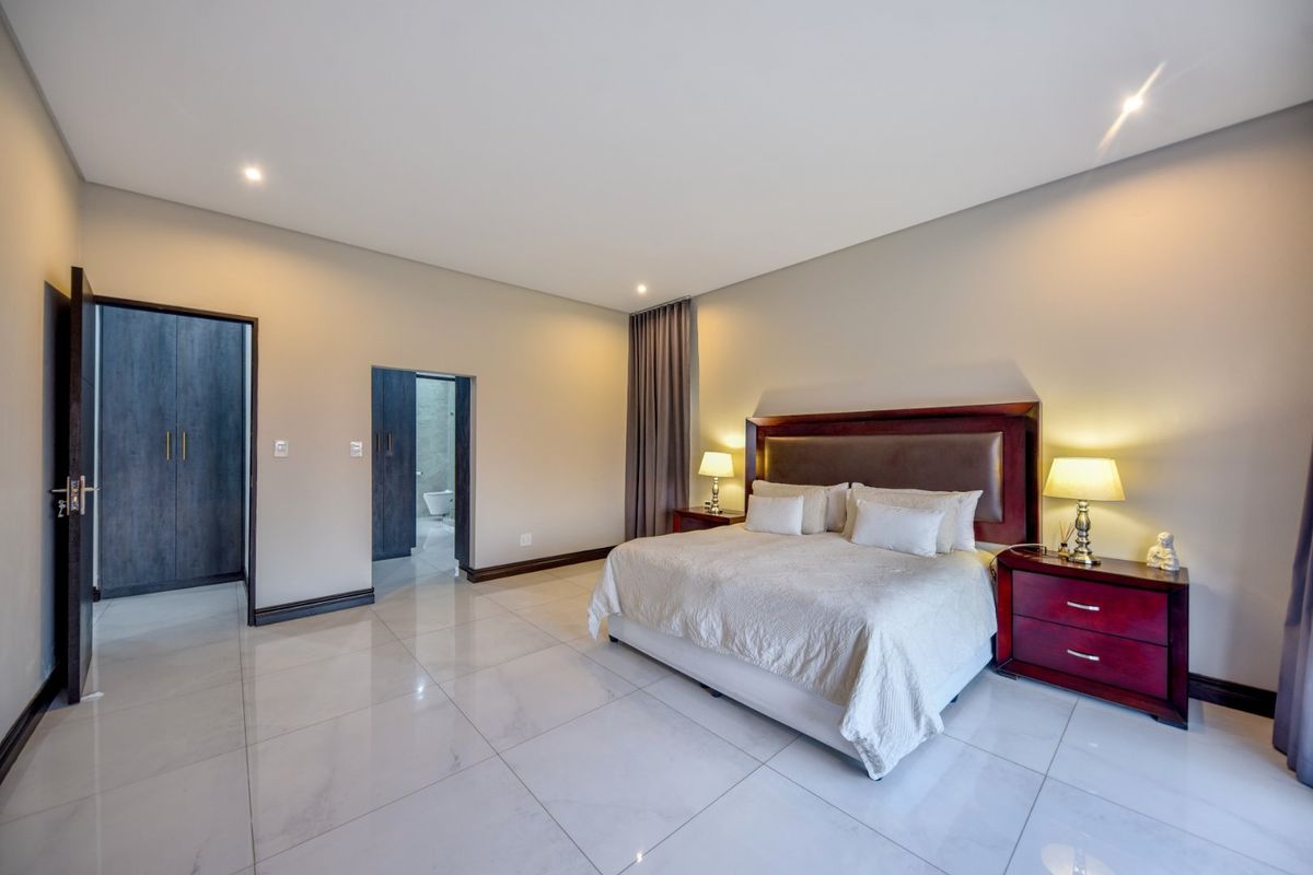 Spacious bedroom featuring large format floor tiles, recessed lighting, and built-in cupboards with direct access to an en-suite bathroom.