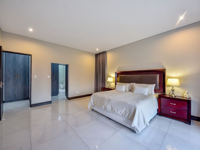 Spacious bedroom featuring large format floor tiles, recessed lighting, and built-in cupboards with direct access to an en-suite bathroom.