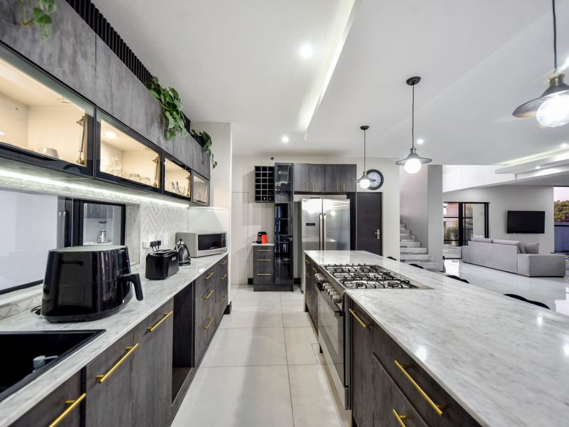 Modern open-plan kitchen featuring a large marble island, gas cooktop, integrated cabinetry, and high-end finishes, seamlessly flowing into the living area.