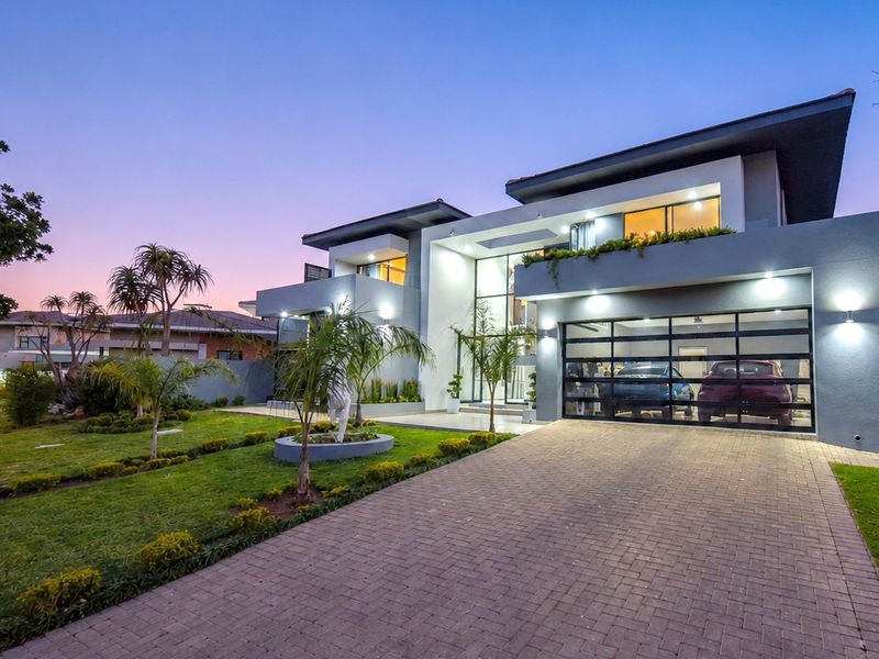 Modern double-story residence featuring a paved driveway, landscaped front garden, and a contemporary facade with a glass-paneled double garage.