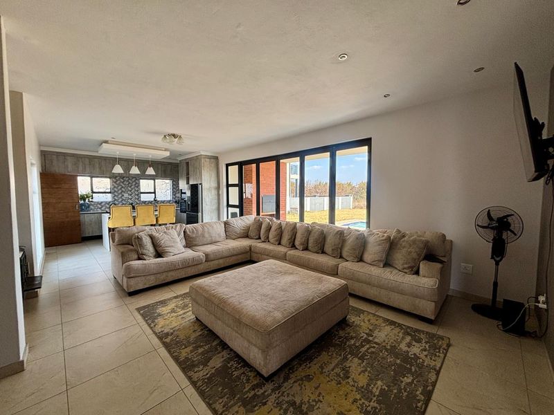 Spacious open-plan living area featuring tiled floors, recessed lighting, and large sliding glass doors that provide seamless access to the outdoor patio and garden.