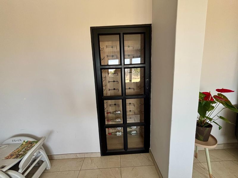 A built-in, glass-fronted wine storage cabinet integrated into the wall, featuring internal shelving and a black frame.