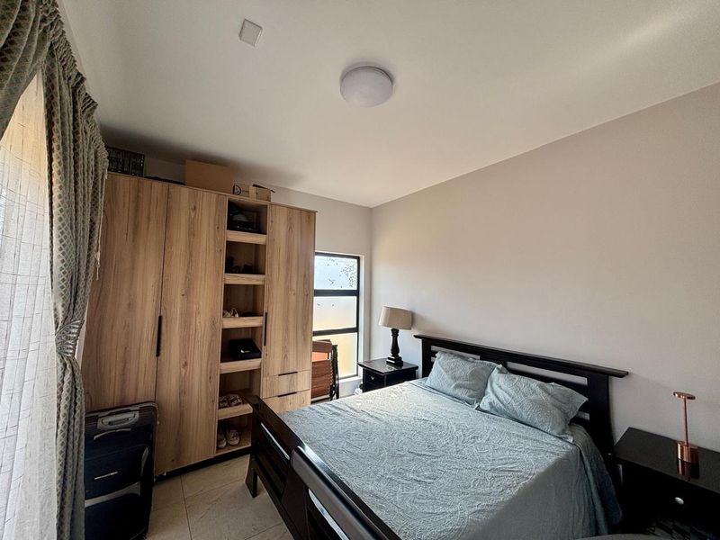 A well-maintained bedroom featuring neutral walls, tiled flooring, and a large built-in wooden wardrobe providing ample storage space.