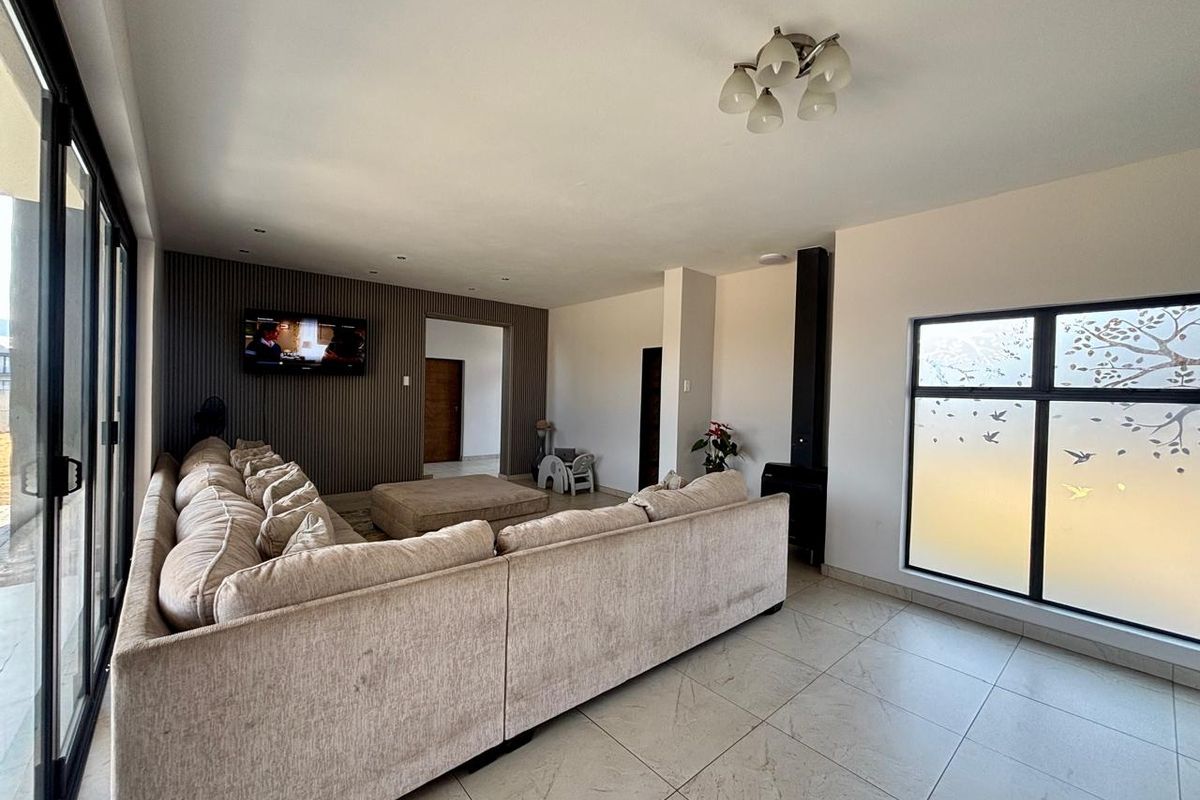 Spacious living room featuring a modern slatted accent wall, large format floor tiles, a freestanding fireplace, and expansive sliding doors leading to the exterior.