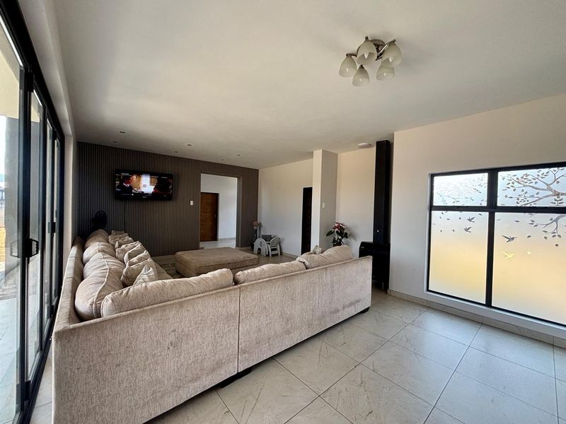 Spacious living room featuring a modern slatted accent wall, large format floor tiles, a freestanding fireplace, and expansive sliding doors leading to the exterior.