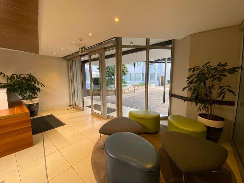 Modern commercial building entrance featuring tiled flooring, recessed lighting, and large sliding glass doors providing access to an outdoor courtyard area.
