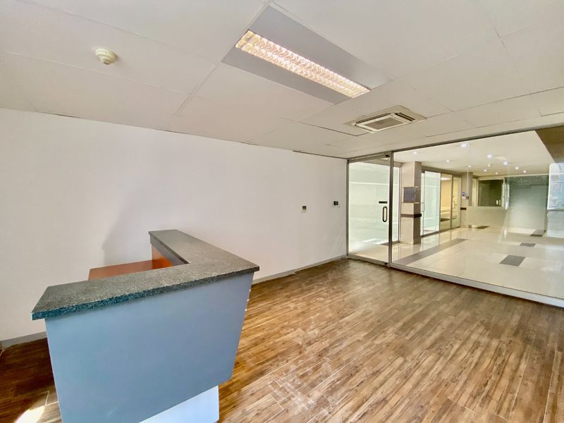 Commercial office space featuring a built-in reception desk, wood-look tile flooring, and glass partition walls providing a bright, professional entrance area.