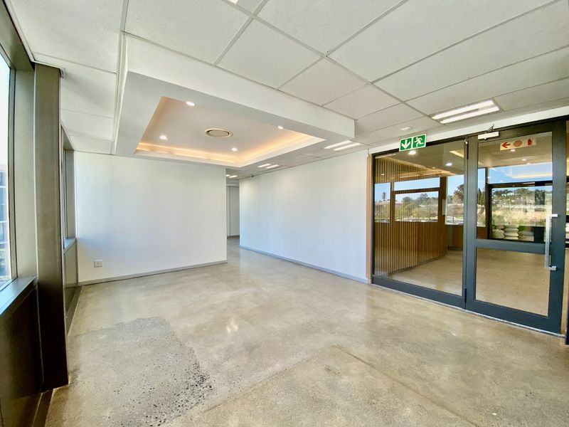 A bright, modern commercial entry space featuring polished concrete floors, a suspended ceiling with recessed lighting, and a glass partition door.