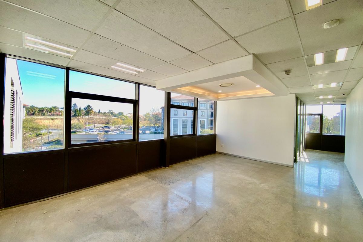 A bright, open-plan commercial office space featuring polished concrete floors, a modern bulkhead ceiling, and large windows providing ample natural light.