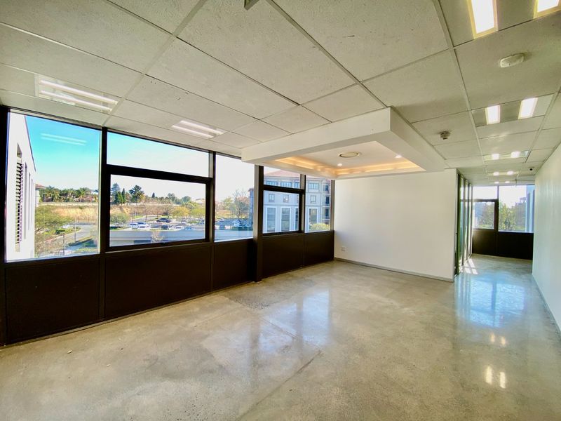 A bright, open-plan commercial office space featuring polished concrete floors, a modern bulkhead ceiling, and large windows providing ample natural light.