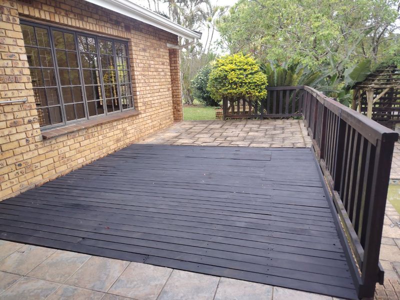 Outdoor patio area featuring a combination of paved flooring and timber decking, enclosed by a timber balustrade with views of the garden.