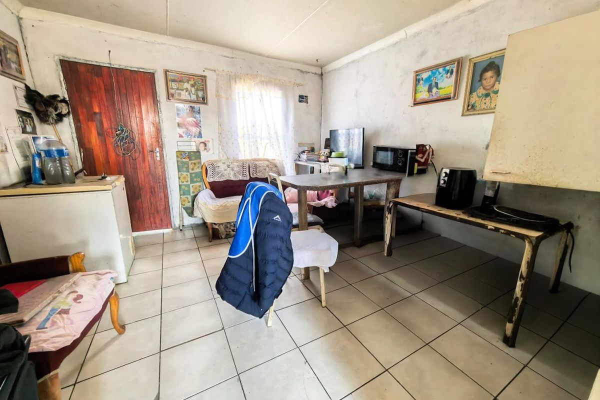 A living area featuring ceramic floor tiles and a timber entrance door, requiring cosmetic updates to the wall finishes and general maintenance.
